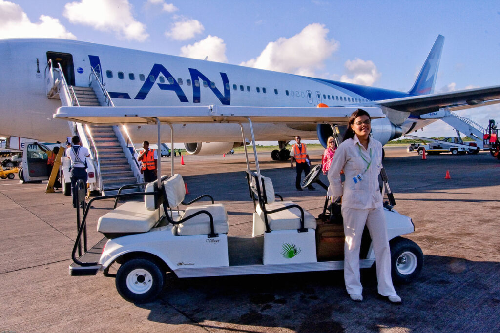 Guests beside a golf cart and a passenger aircraft at Punta Cana Airport.