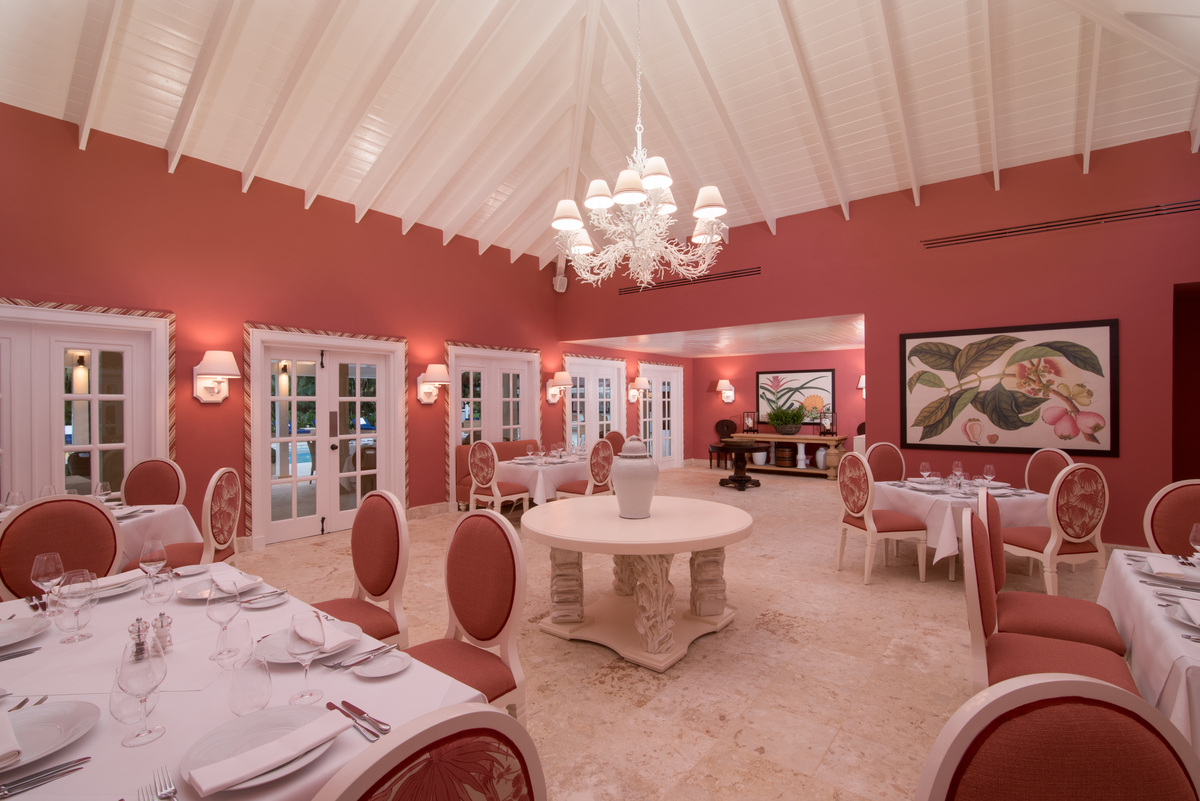 Coral-coloured dining room with round tables and a chandelier at Bamboo.