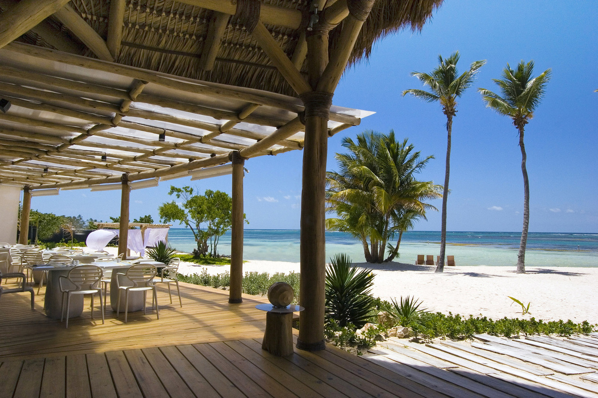 Shaded dining terrace overlooking white sand, palms and turquoise water at Playa Blanca.
