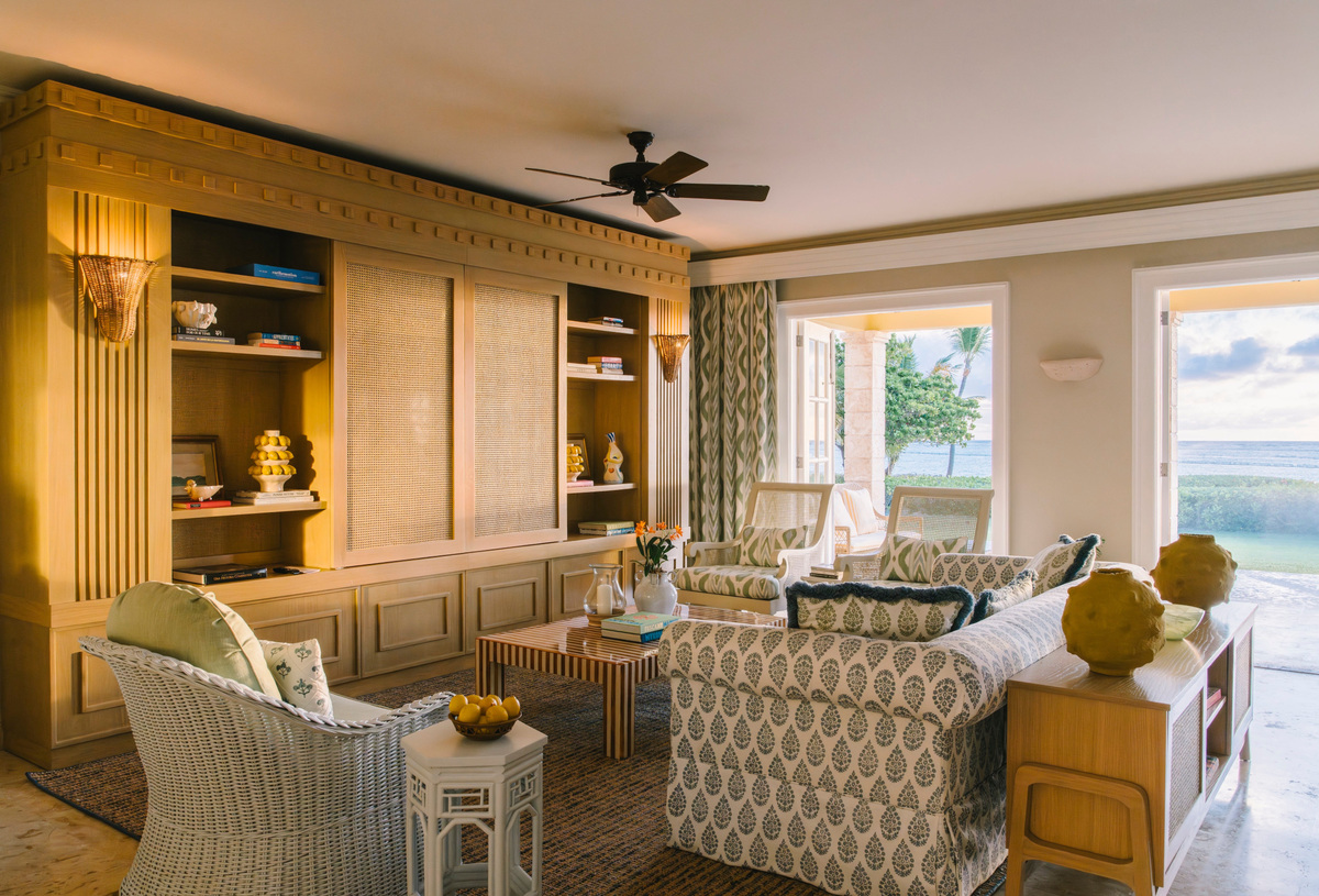 Seating, wooden cabinetry and open doors facing the sea in a Tortuga Bay sitting room.