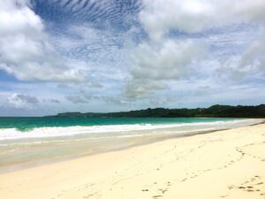 White sand and turquoise waves beneath clouds at Playa Rincón.