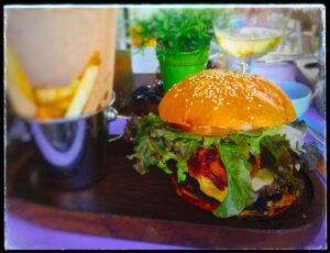 A burger and a metal cup of chips at Noah Restaurant & Lounge.