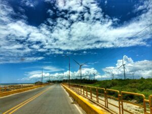 A road passes rows of wind turbines beneath patterned clouds at Los Cocos.