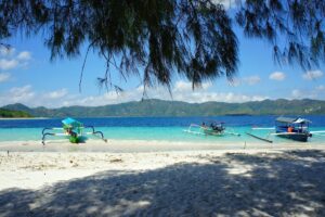 Outrigger boats beside a white-sand shore on the Gili islands.