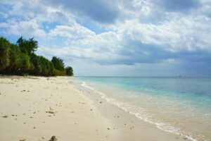 A quiet sandy beach and pale blue water on the Gili islands.