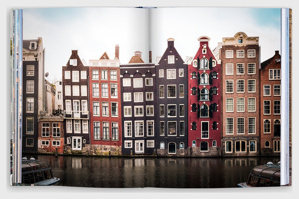 An open spread showing a row of narrow brick canal houses in red, brown and black above dark canal water.