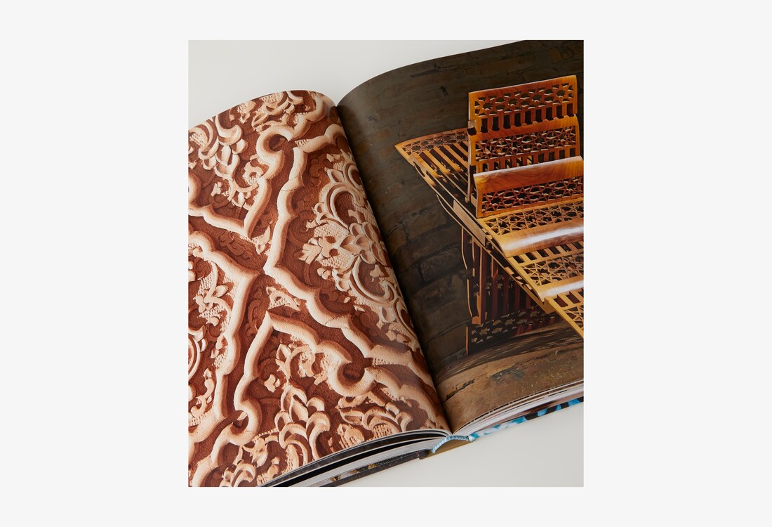 A close view of the open book showing embroidered fabric and a carved wooden stand.
