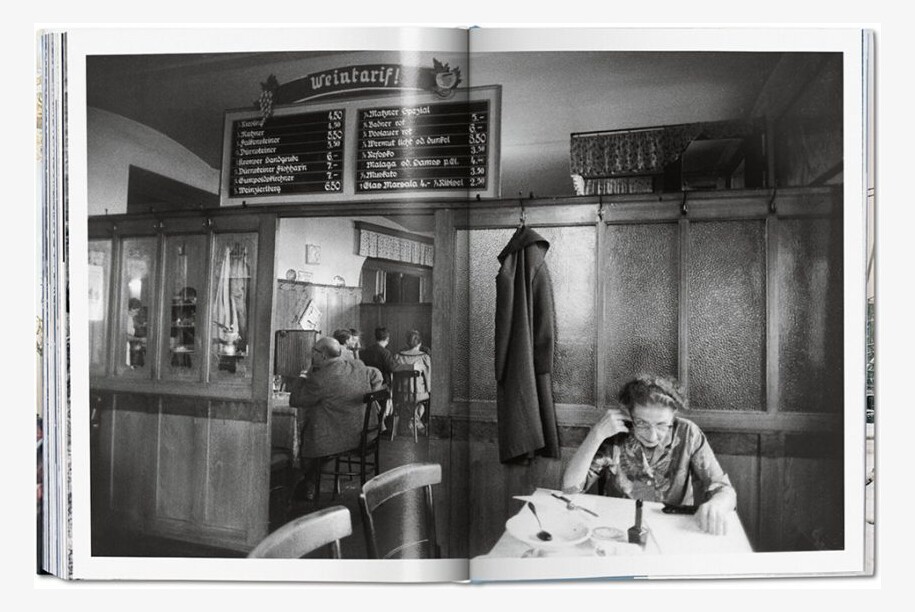 An open spread with a black-and-white photograph of people seated in a wood-panelled Viennese wine tavern.