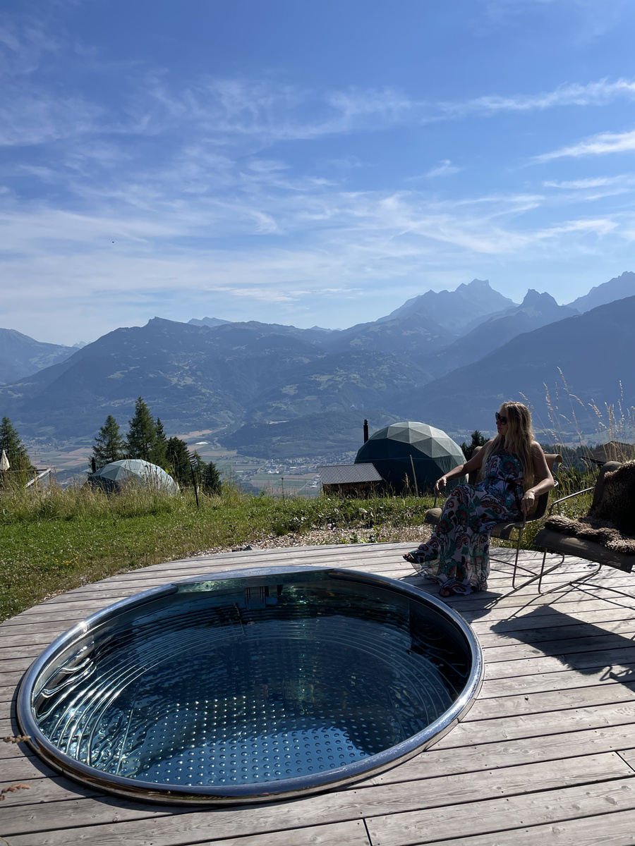 A guest seated beside the outdoor bath with the mountains beyond.
