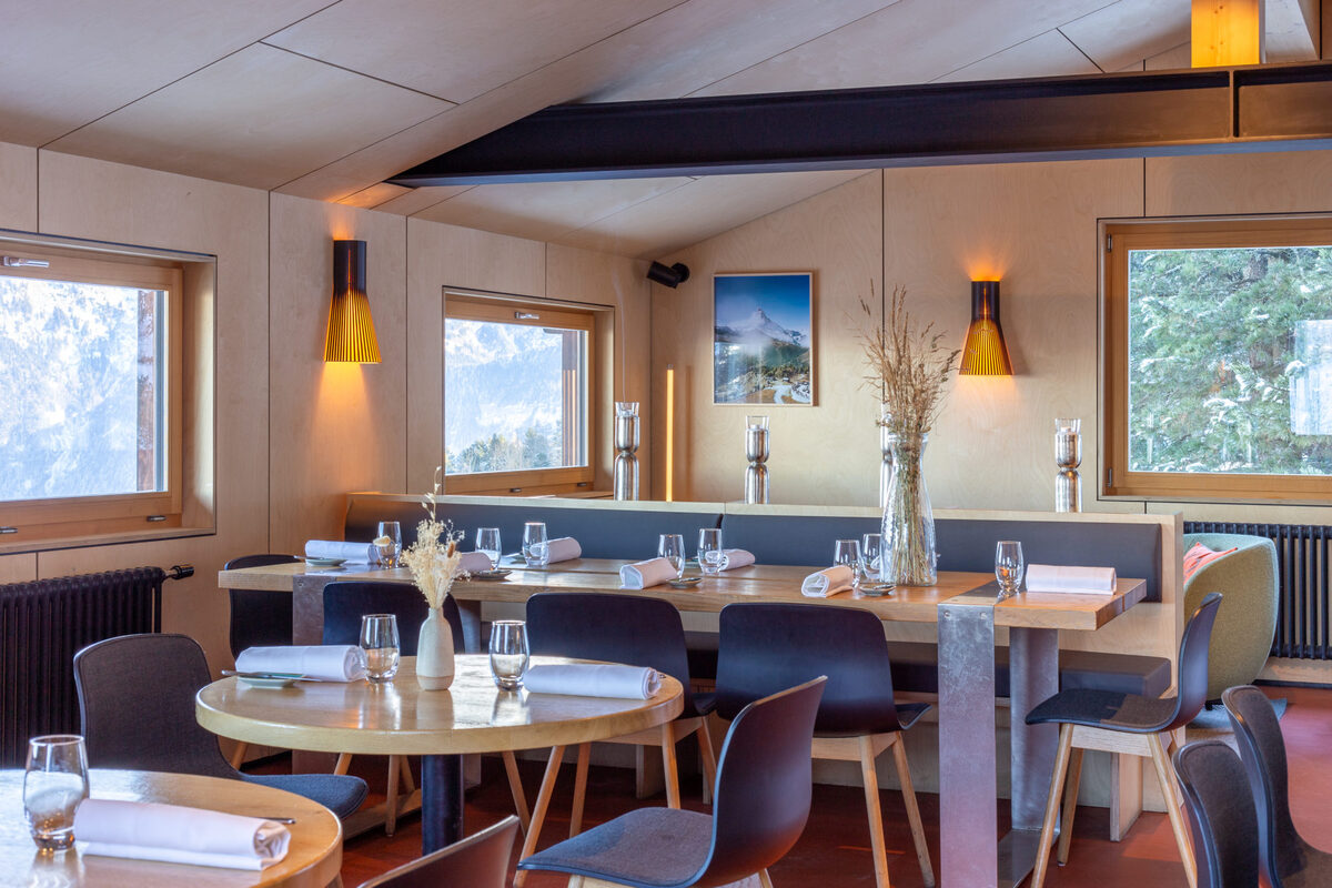 Tables set for dinner in a wood-panelled dining room at Les Cerniers.
