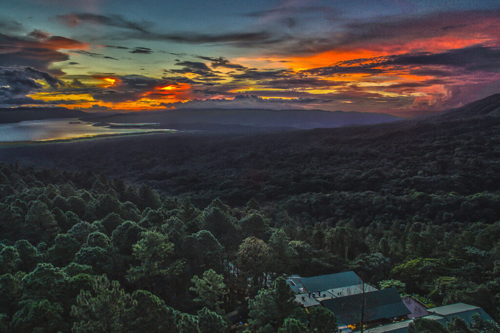 An aerial view of the lodge’s roofs and surrounding forest, with Lake Arenal at sunset.