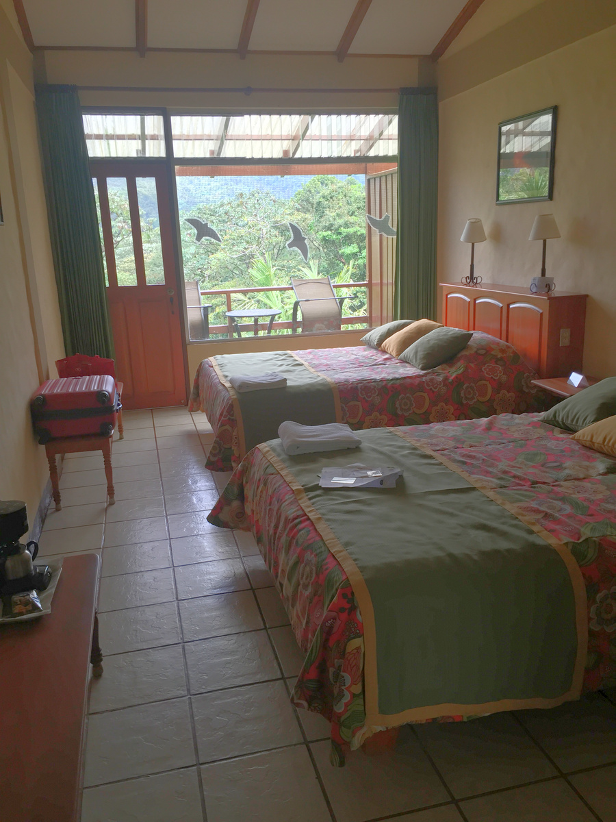 My room at Arenal Observatory Lodge, with two beds and a glazed wall opening towards the balcony.