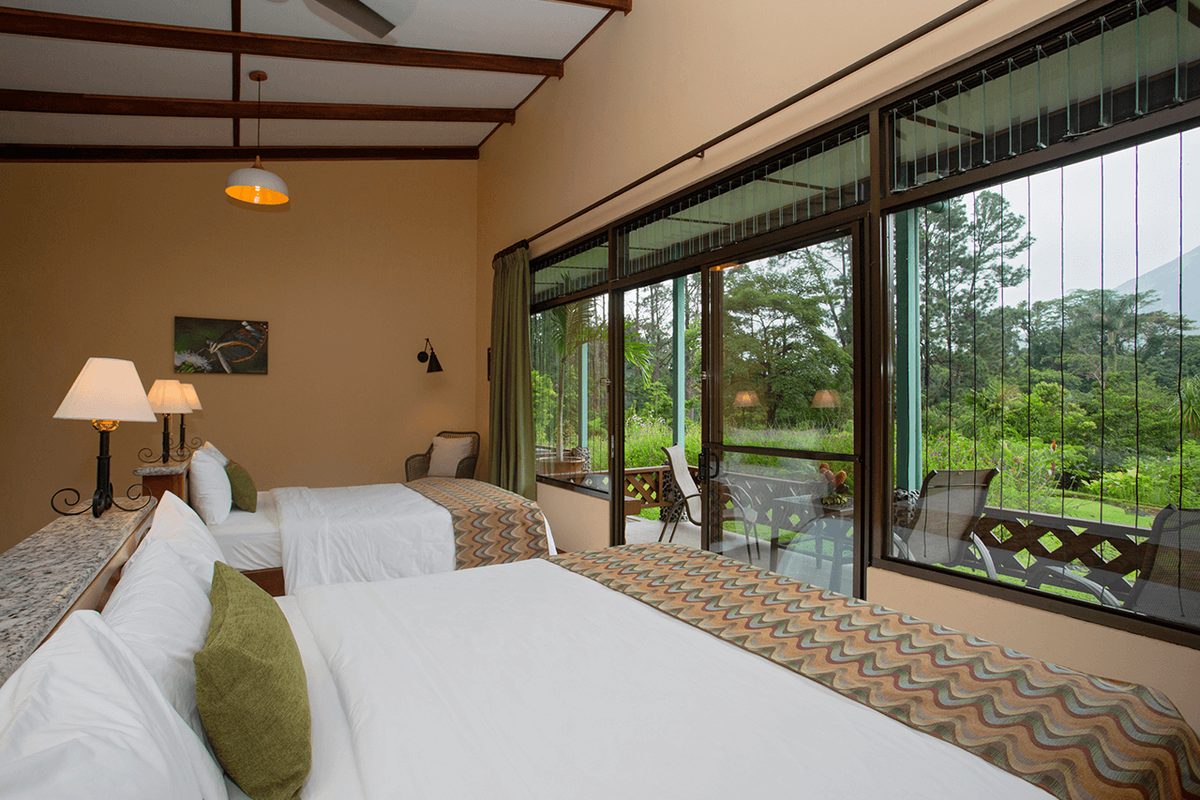 A Smithsonian room with two beds and broad windows opening towards its terrace and the forest.