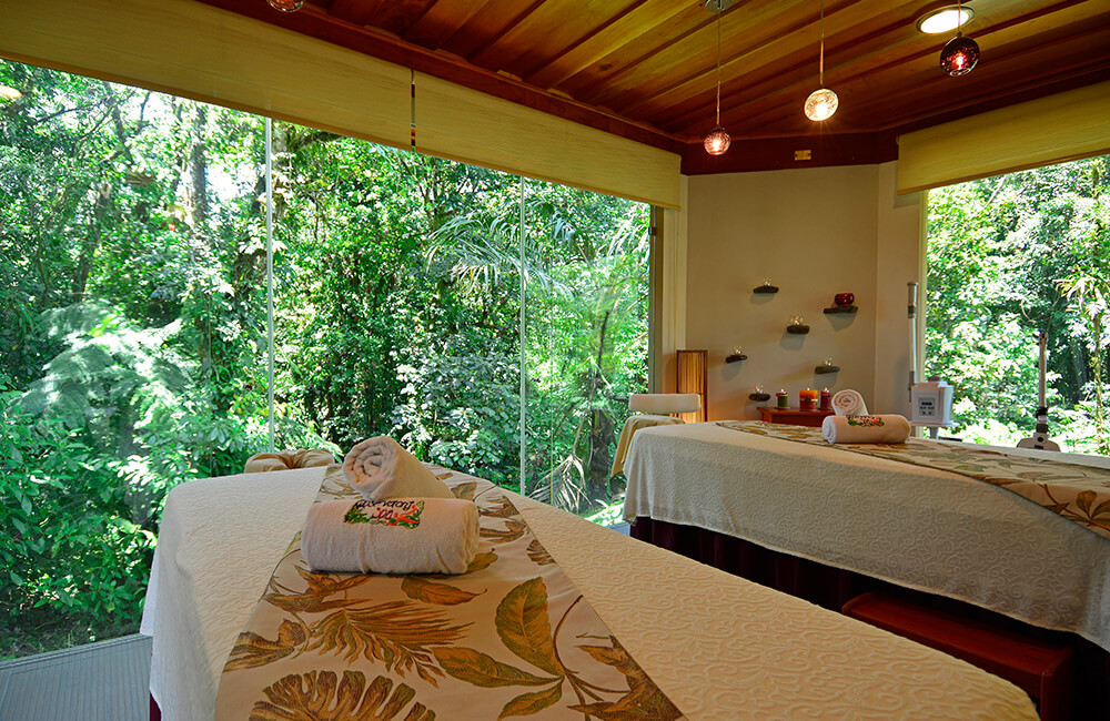 An empty Observatory Spa treatment room with two beds and broad windows facing the rainforest.