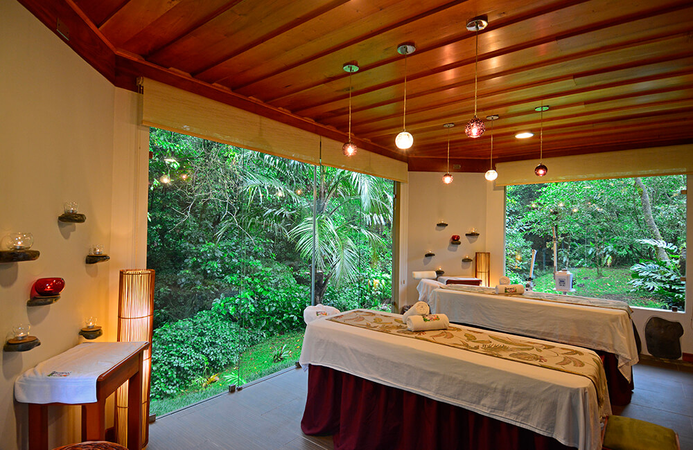 Two treatment beds in the Observatory Spa beside windows overlooking dense greenery.