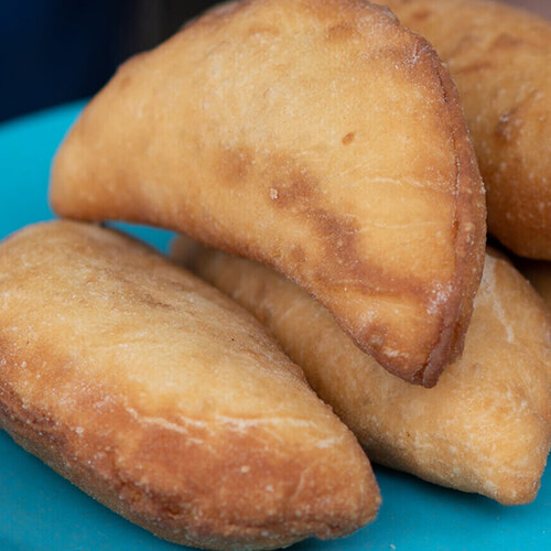 Golden half-moon pastries piled on a blue plate.