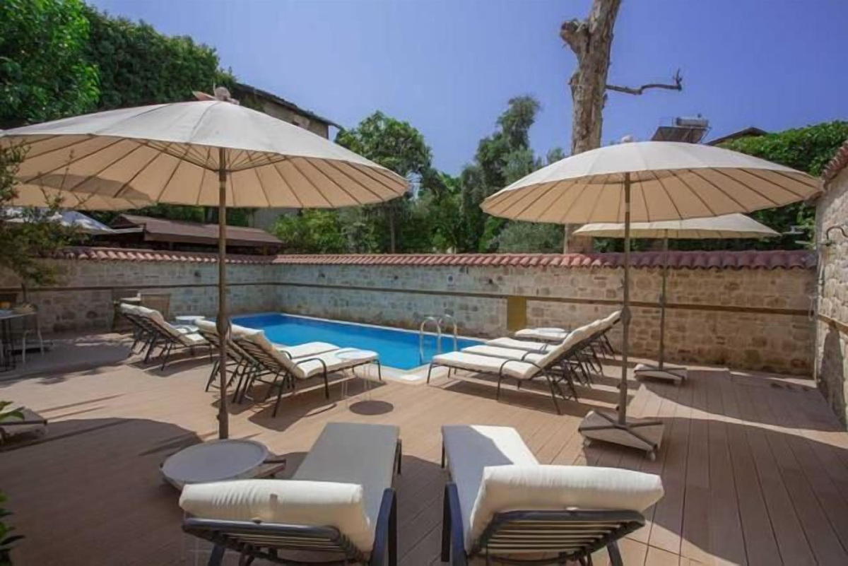 A small outdoor pool with loungers and parasols within the stone-walled courtyard at Char Me.