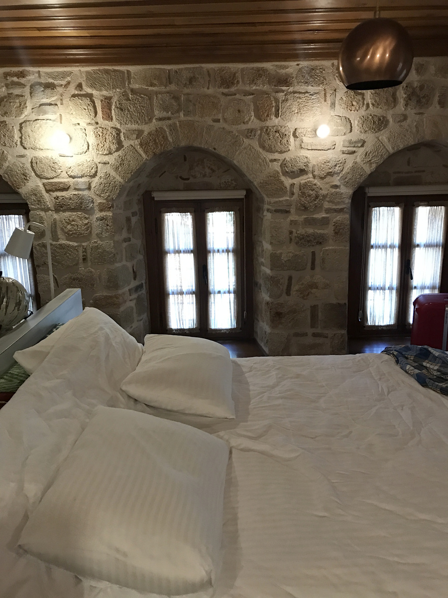 The bed beside arched windows and exposed stone walls in our Deluxe Room at Char Me.