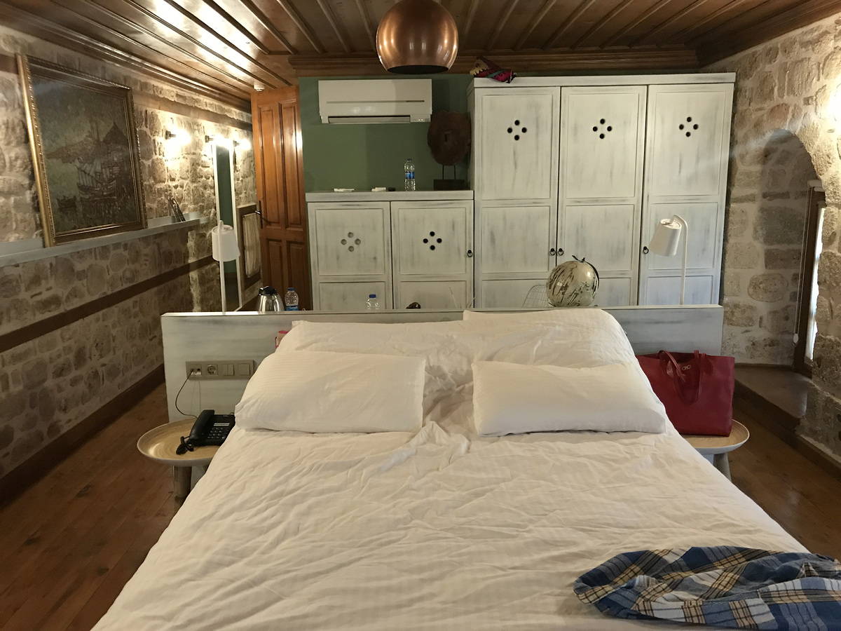 A double bed, white wardrobe, writing table and air conditioner in our Char Me Deluxe Room.