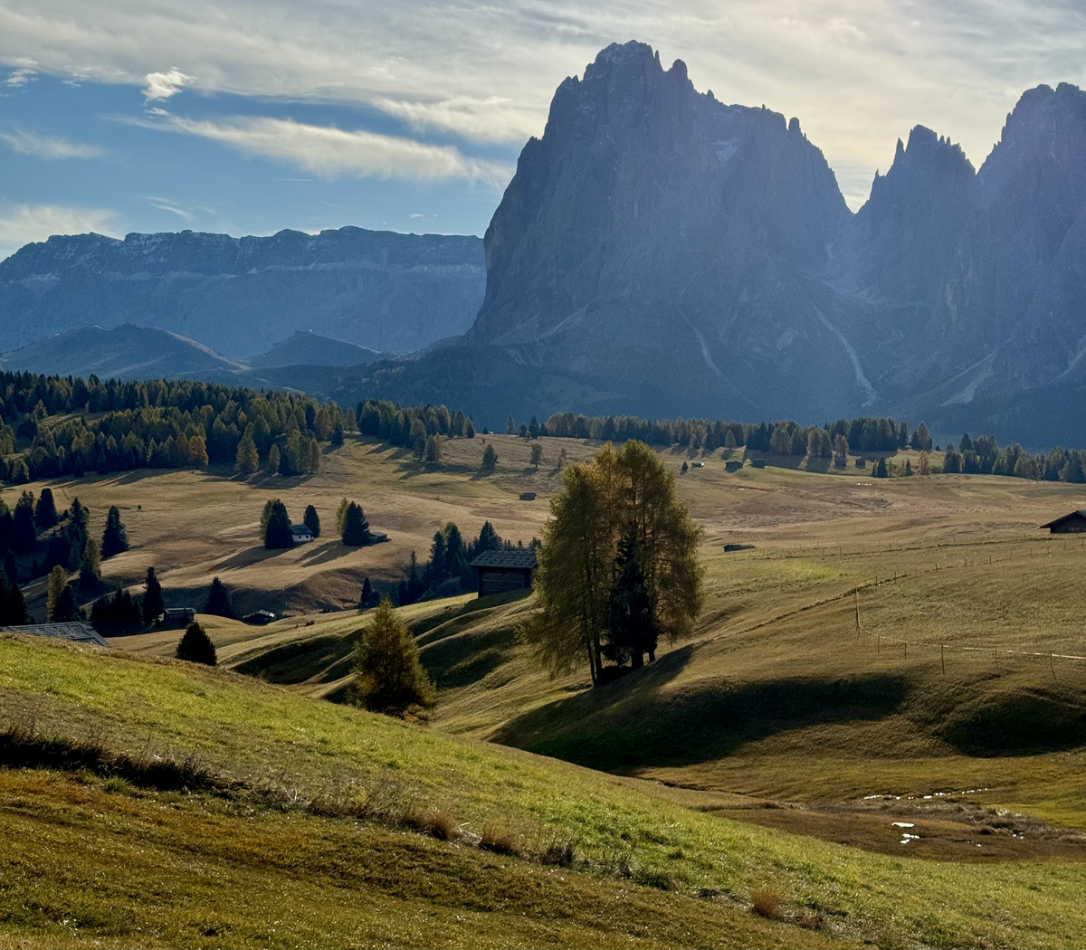 Alpine meadows and wooden huts beneath the Sassolungo peaks at Alpe di Siusi.