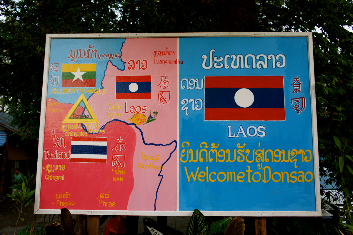 A painted map of the Golden Triangle beside a Lao flag and the words “Welcome to Donsao”.
