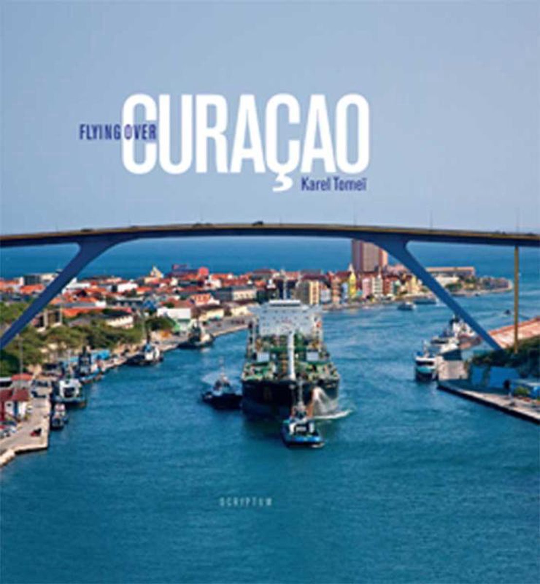 The blue cover of Flying over Curaçao by Karel Tomeï, showing a ship beneath Willemstad’s high bridge.