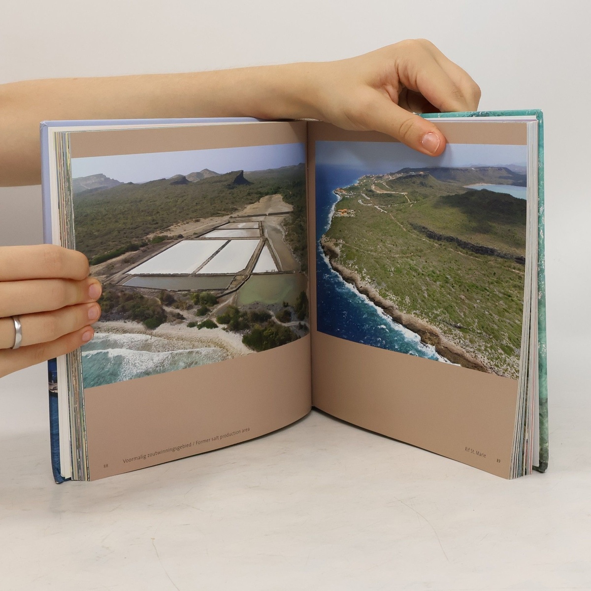 An open spread from Flying over Curaçao, showing aerial photographs of salt pans and a rocky coastline.