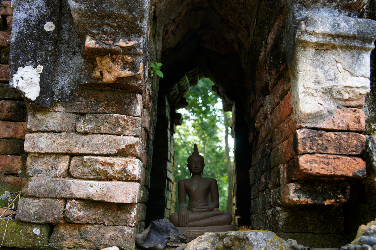 A seated Buddha inside a weathered brick arch at a temple above the Golden Triangle.