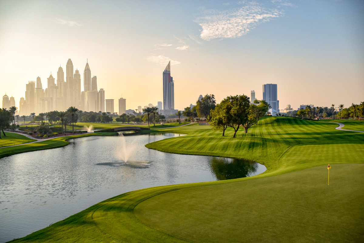 A lake and closely mown fairways at the Majlis Course with Dubai Marina towers on the horizon.