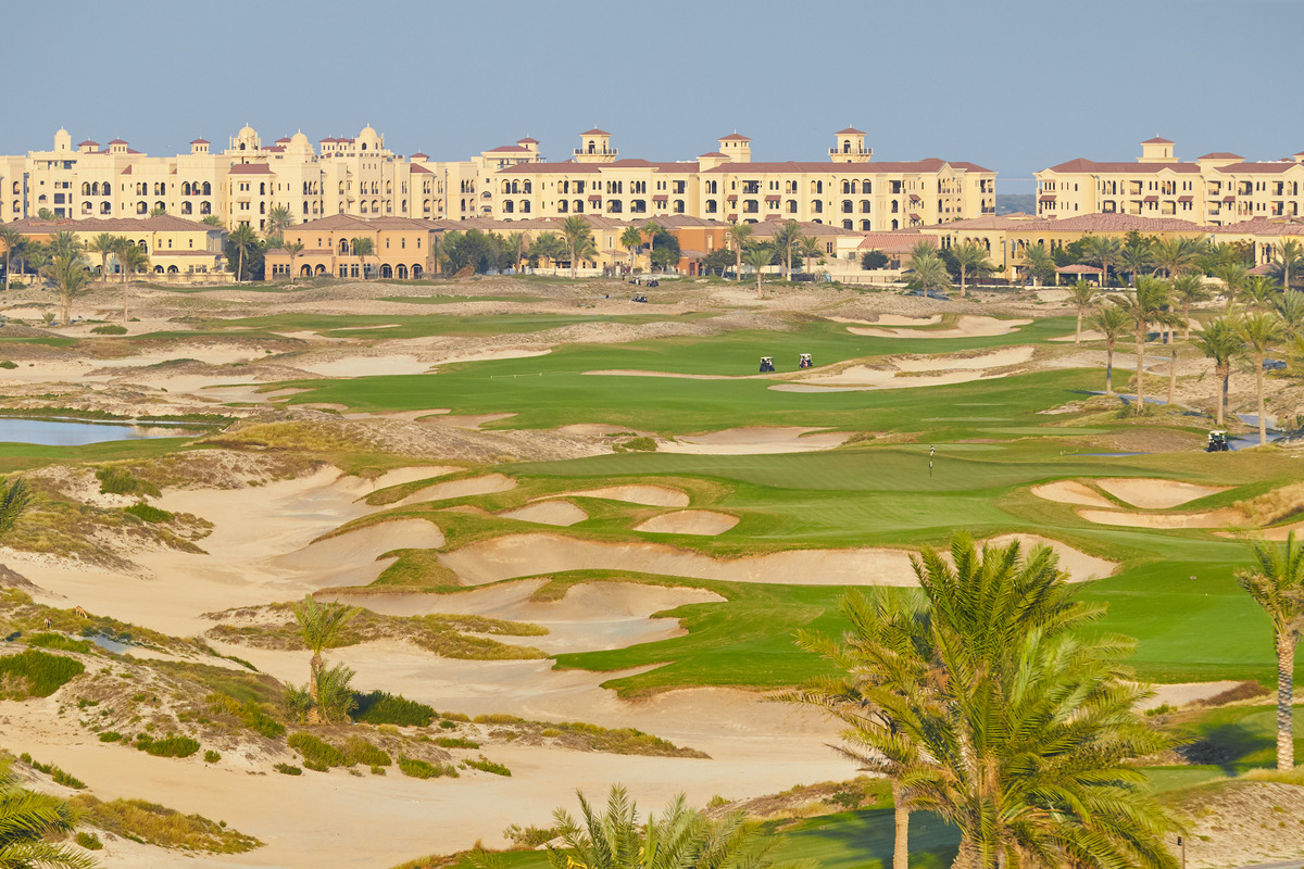 Sweeping sand bunkers divide green fairways in front of The St. Regis Saadiyat Island Resort.