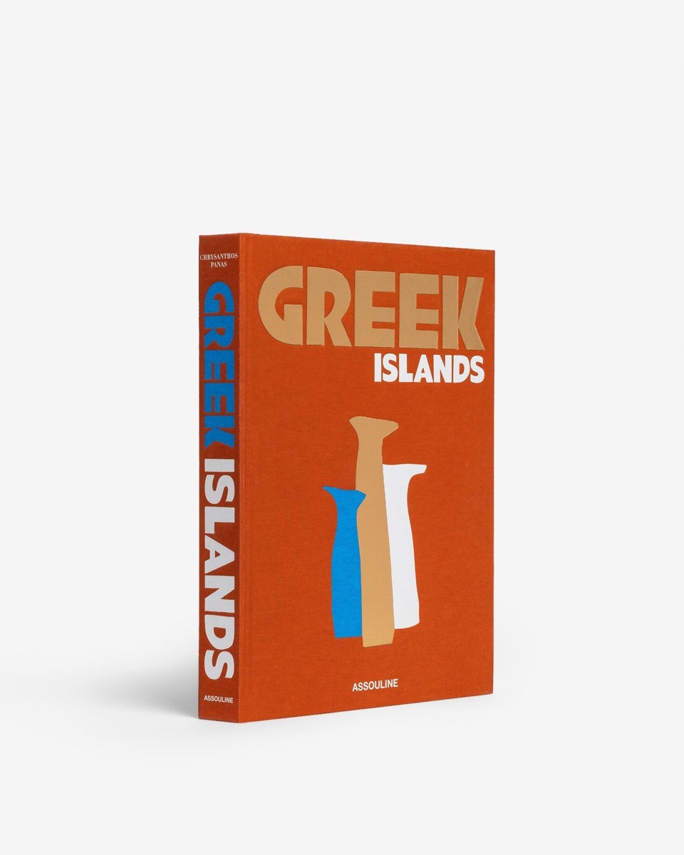 The Greek Islands hardcover by Assouline, in burnt-orange linen with sand and white lettering and three blue, sand and white vases, its spine visible.
