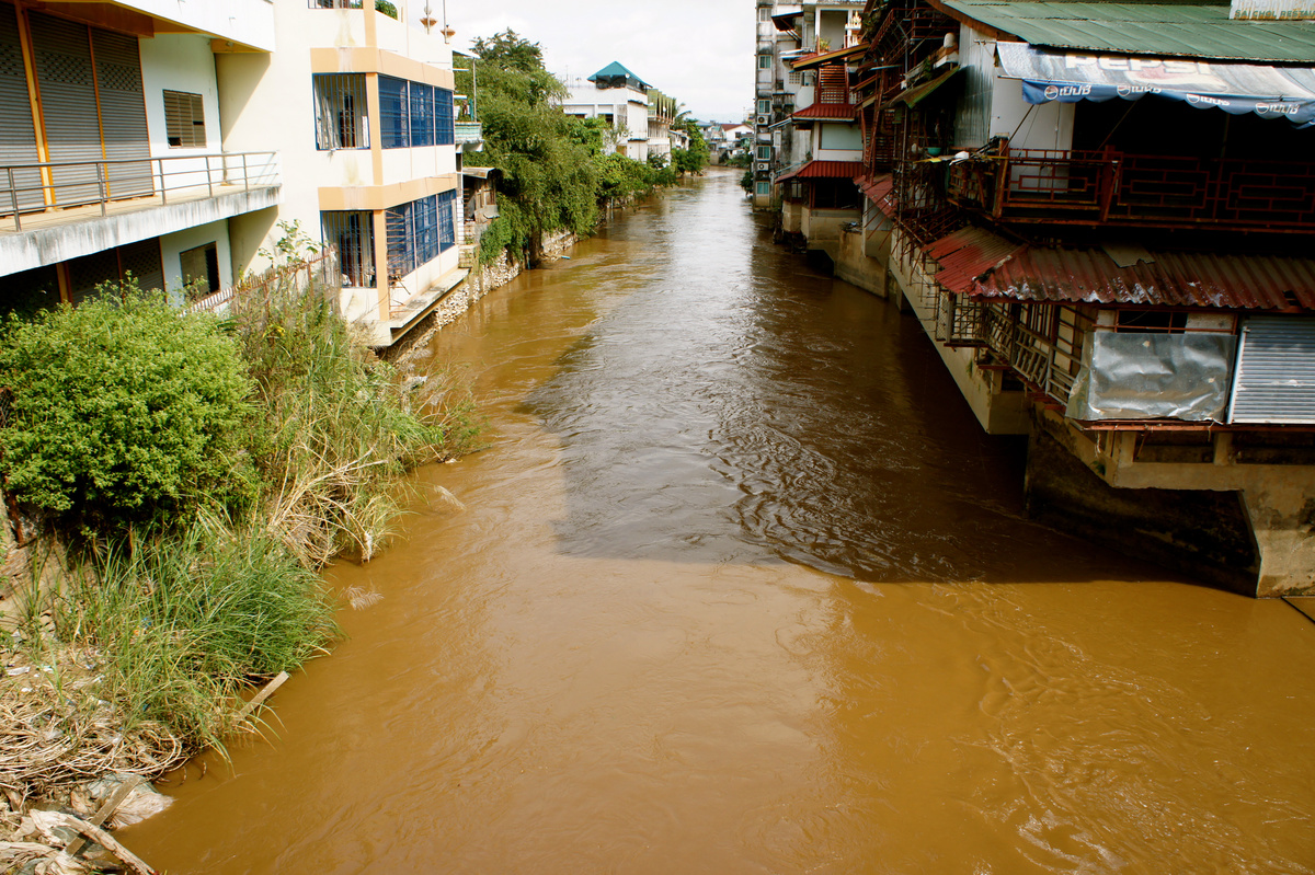 A brown river runs between closely built shops and houses beside the Mae Sai–Tachilek crossing.