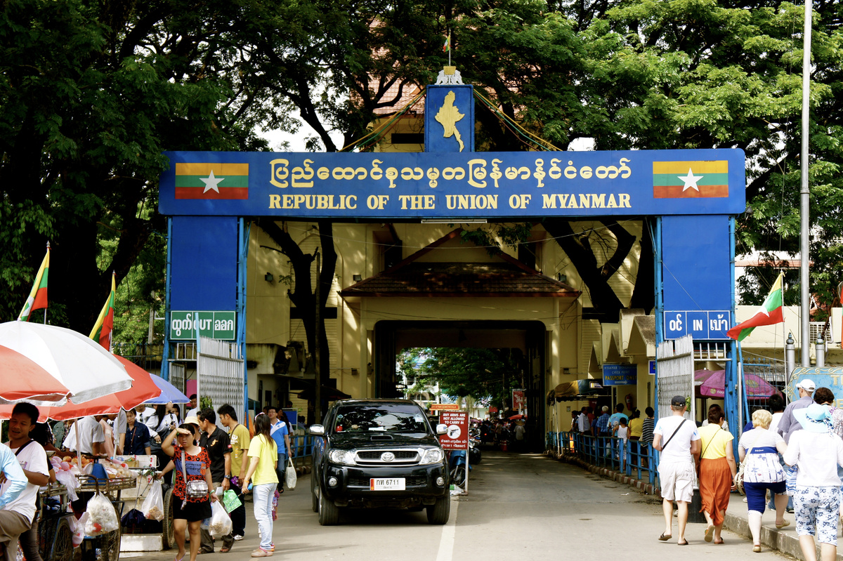 The Myanmar border gateway at Mae Sai and Tachilek, with vehicles and pedestrians beneath a blue sign.