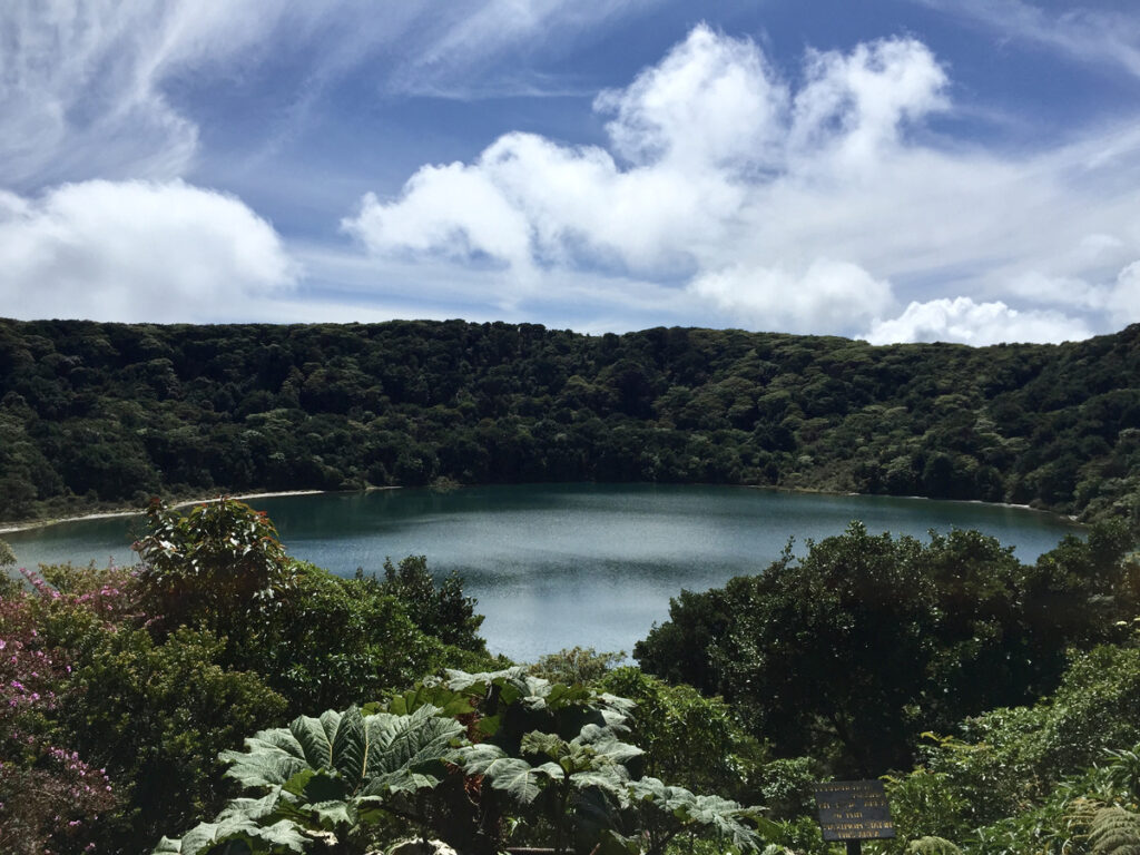 Botos lagoon surrounded by forest below clouds at Poás Volcano