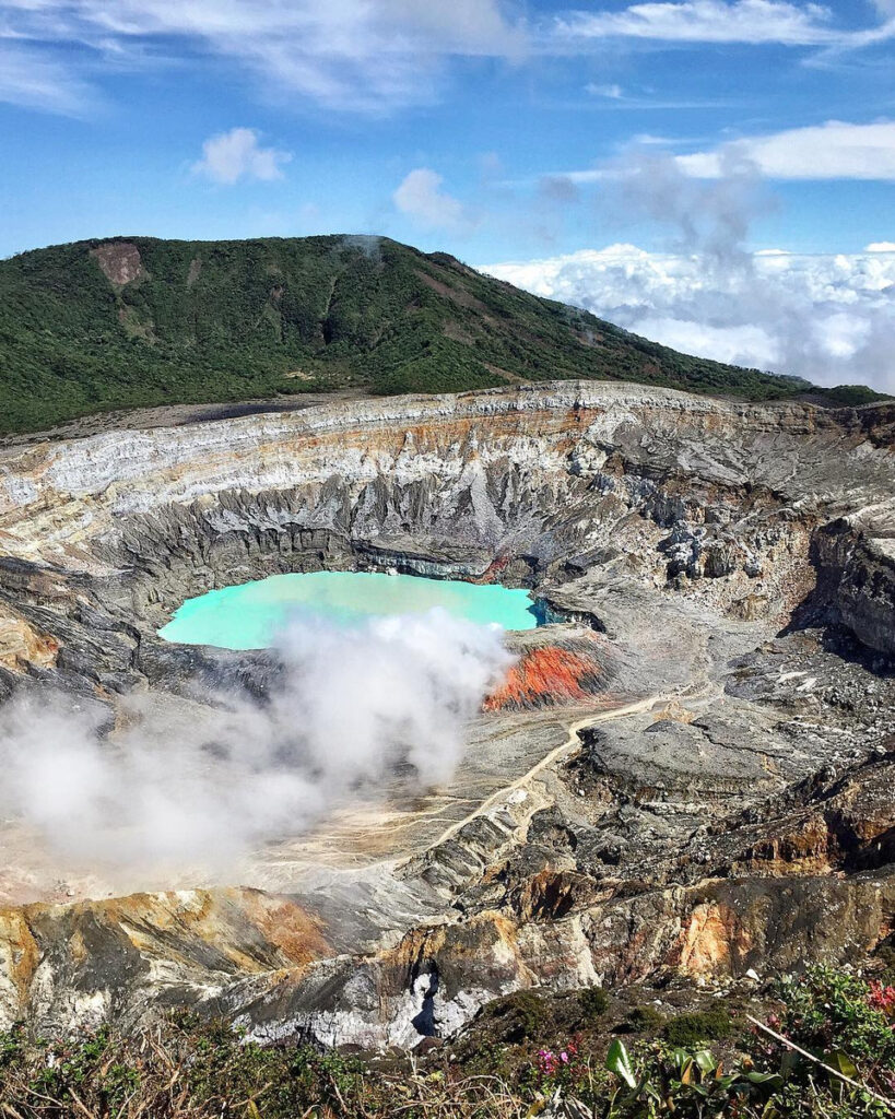 Steam rising from the turquoise lake in the rocky main crater of Poás Volcano