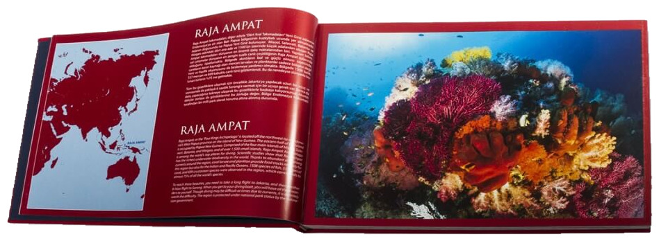 The book open at its introduction, a map locating Raja Ampat beside Turkish and English text, facing a reef of pink and orange soft corals.