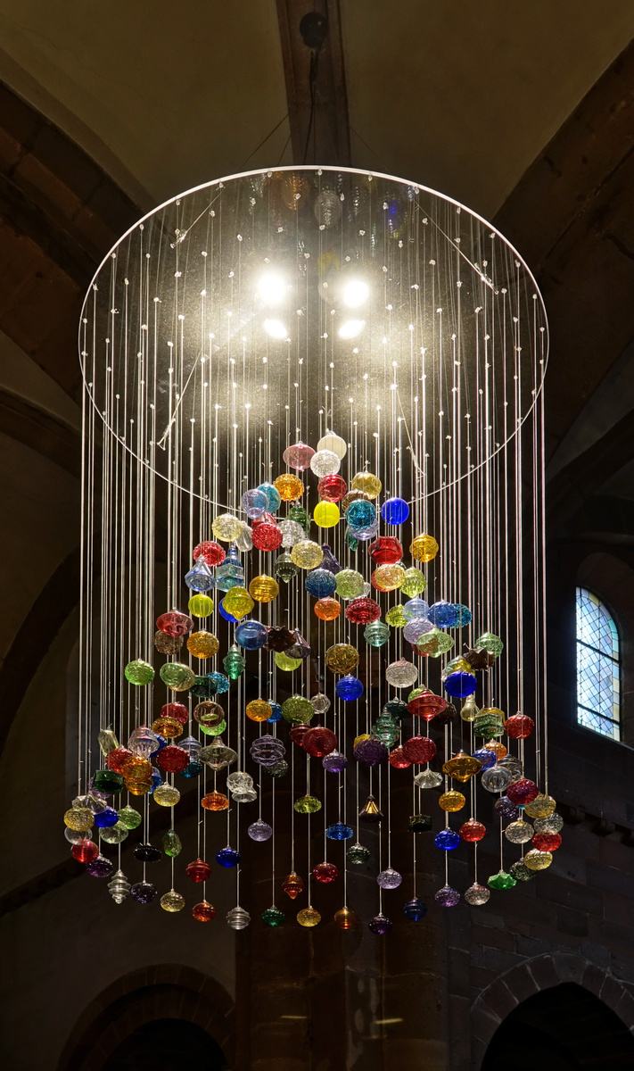 Colourful Meisenthal glass Christmas ornaments suspended in a tree-shaped chandelier inside Sainte-Foy church.