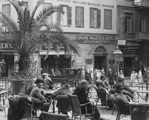 Guests sit in wicker chairs on the terrace of Shepheard’s Hotel, overlooking a Cairo street.