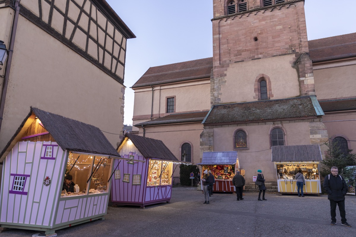 Colourful crooked wooden stalls at Turckheim’s Marché des Lutins beneath the stone tower of Sainte-Anne church.