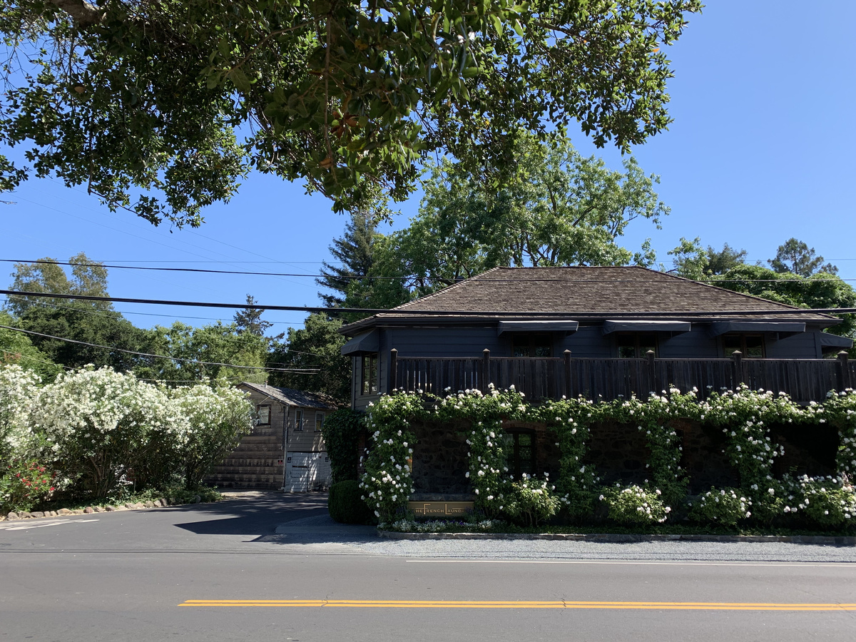 The French Laundry’s stone and timber facade covered with flowering climbing plants on Washington Street.