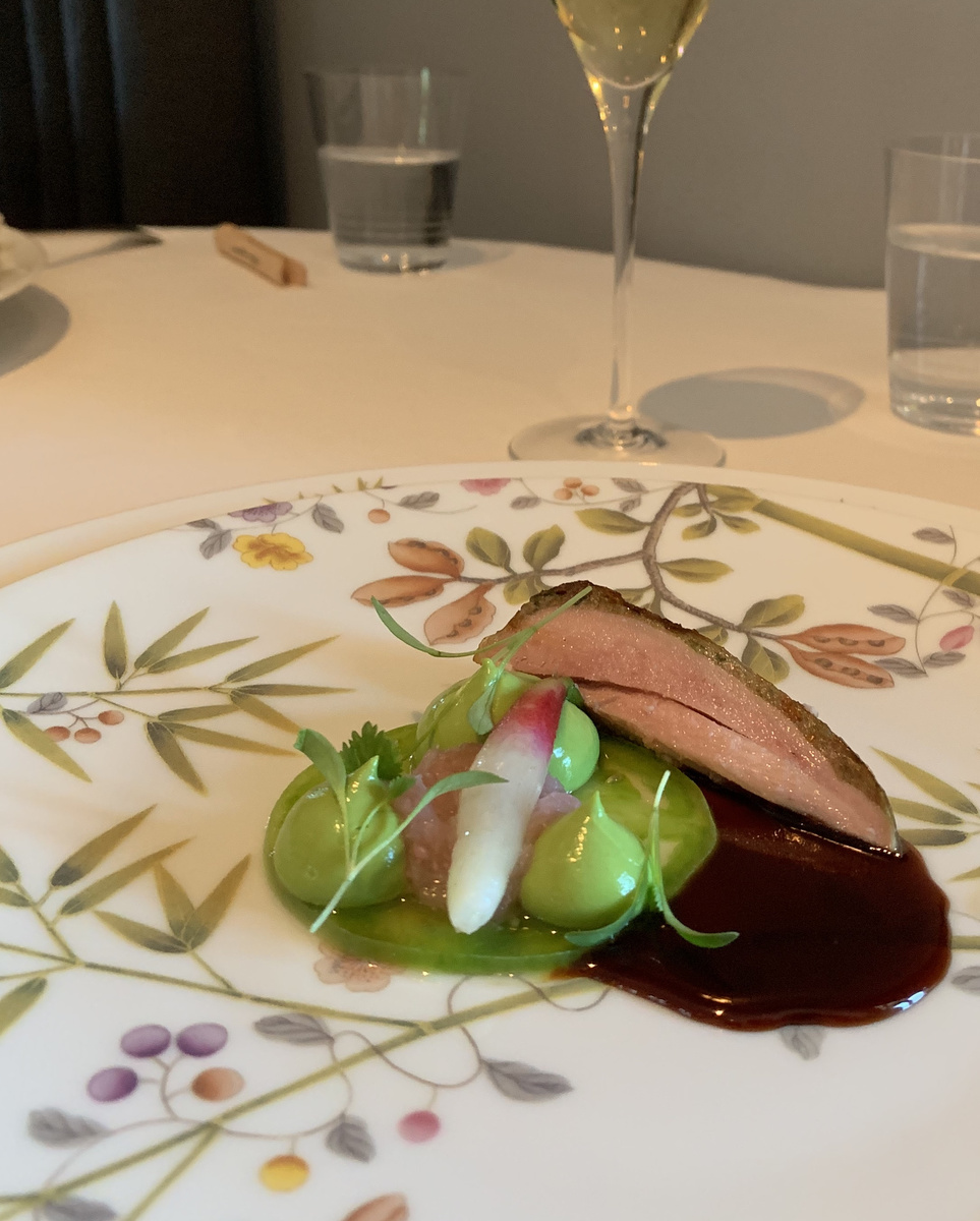 Slices of meat with vegetables and dark sauce on a floral plate at The French Laundry.