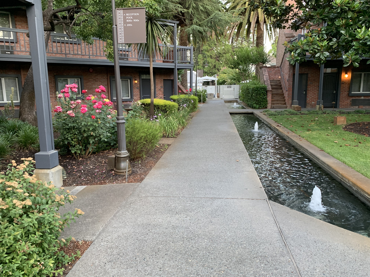 Garden path beside a narrow fountain channel and brick guest buildings at Vintage House.