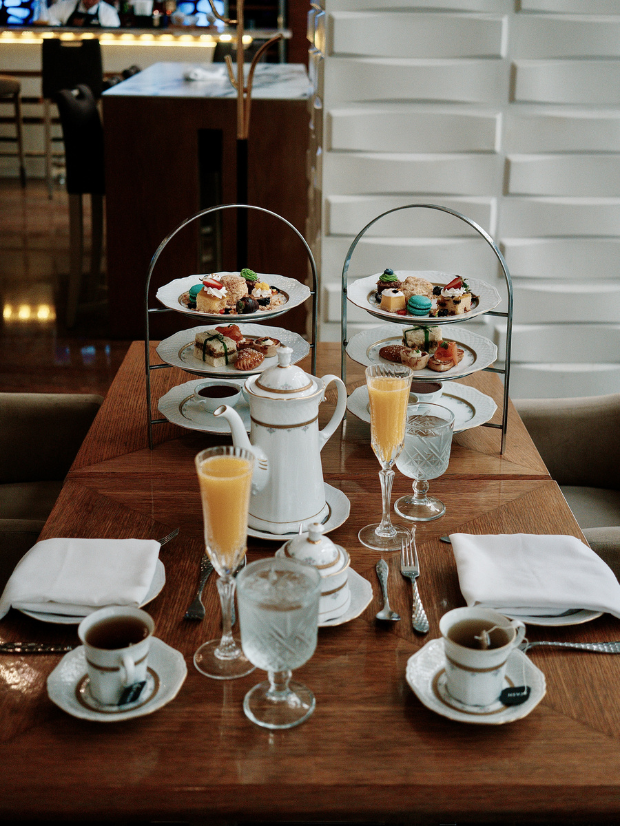 Two tiered stands of sandwiches and pastries beside teapots and cups at Peacock Alley.