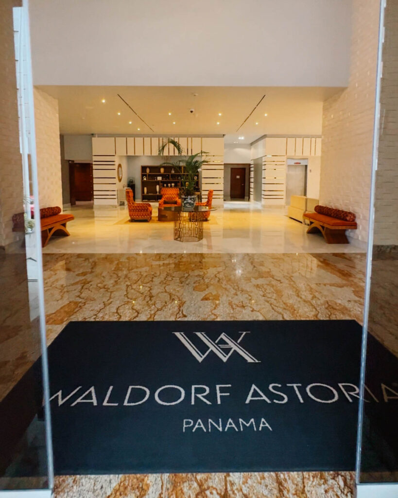 Entrance to Waldorf Astoria Panama, with its name on a floor mat and a seating area beyond.