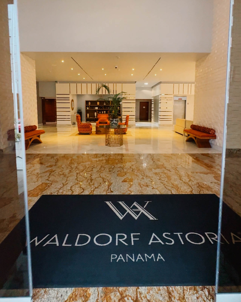 Entrance to Waldorf Astoria Panama, with its name on a floor mat and a seating area beyond.
