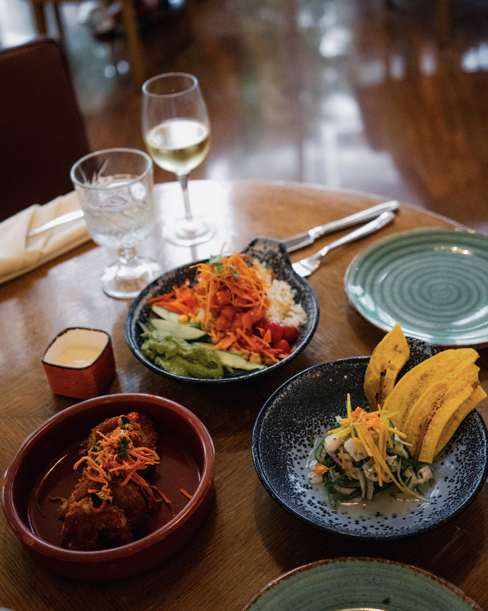 Bowls and small plates on a restaurant table, with glasses and a green plate beside them.