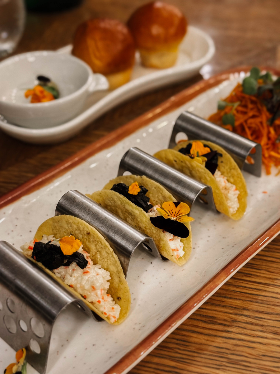 Three small tacos with flower garnishes served on a long ceramic plate at Waldorf Astoria Panama.